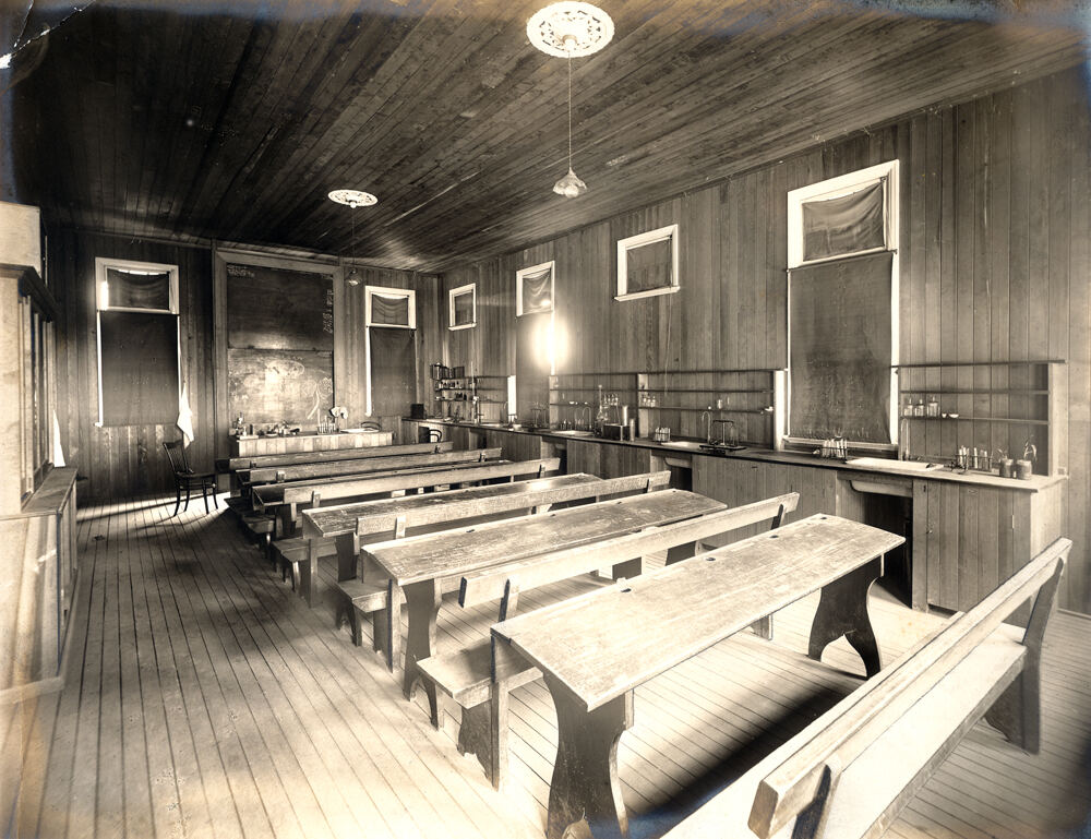 A vintage classroom with wooden desks and science equipment shows historic girls' education.